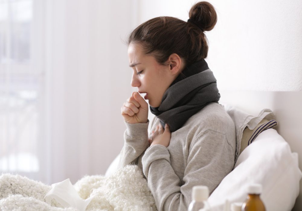 A woman with a cold coughing on her couch.