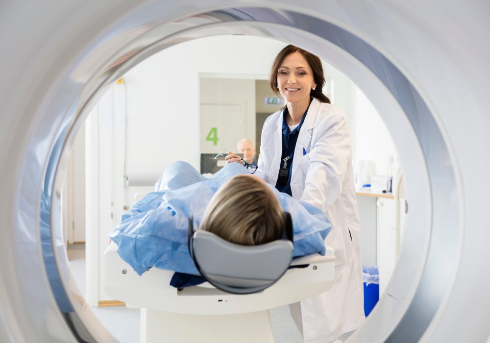 A patient undergoing an MRI scan as an MRI tech looks on.