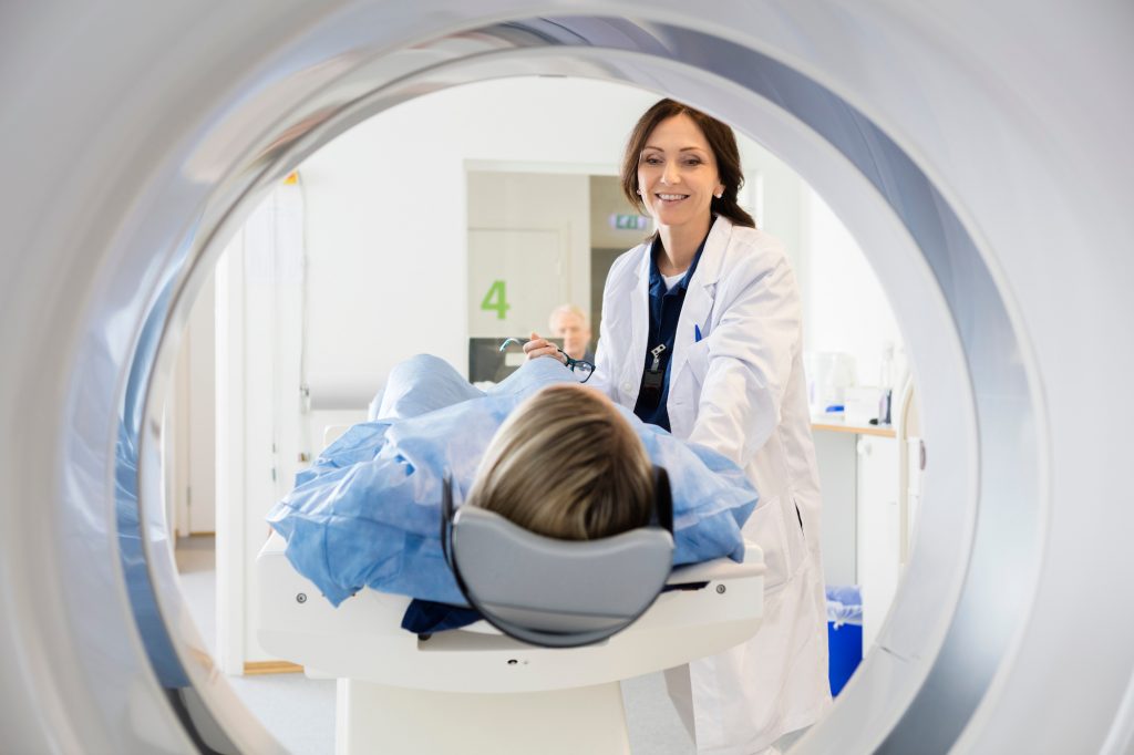 A patient undergoing an MRI scan as an MRI tech looks on.